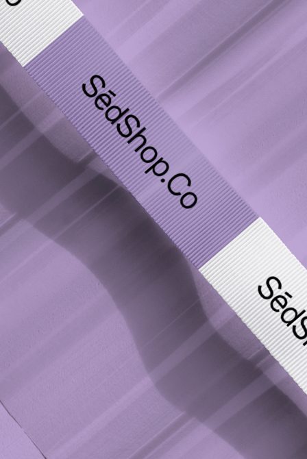 Elegant purple fabric texture with shadow effects and white branding ribbon, ideal for graphic design mockups and material presentations.